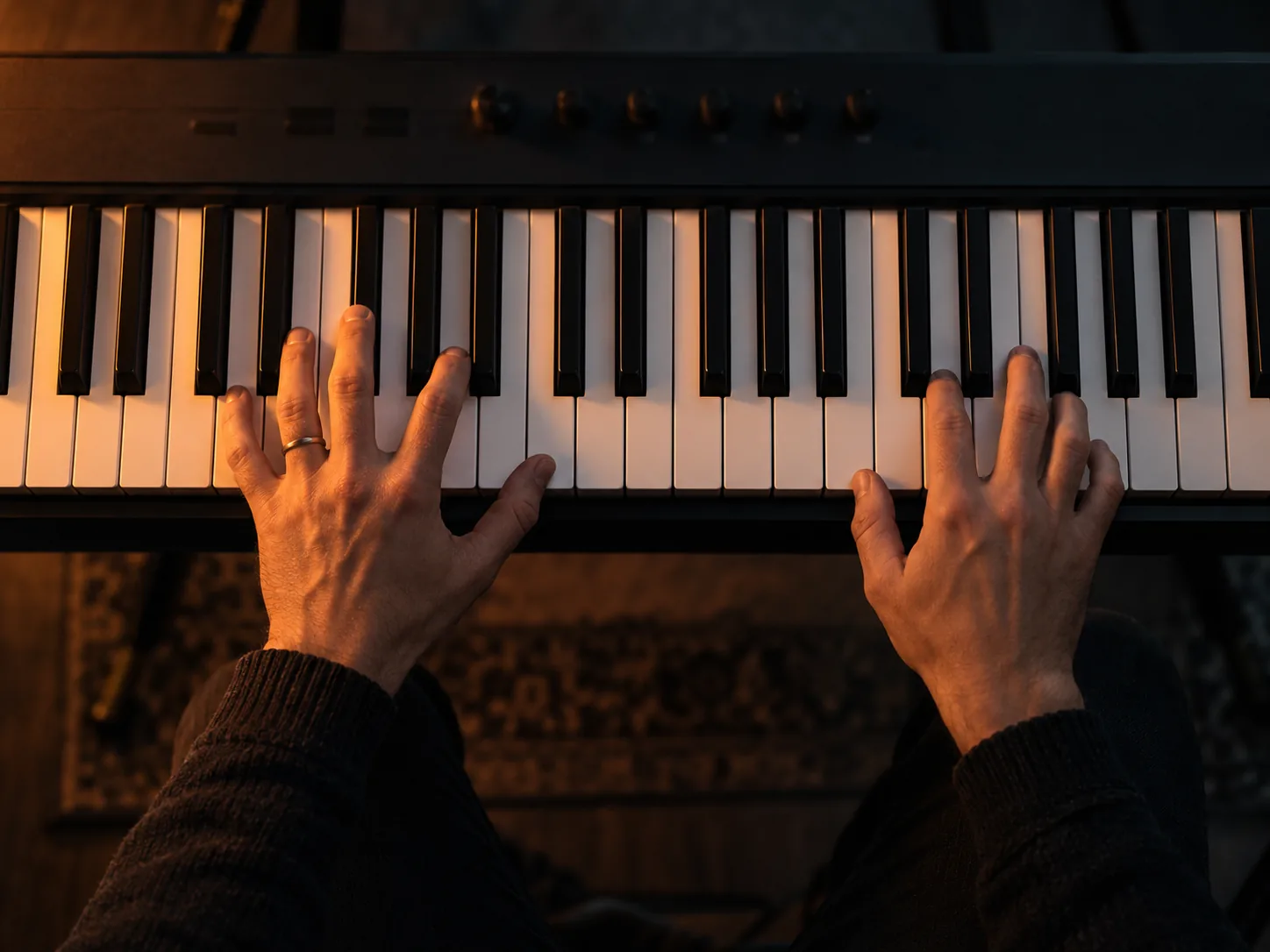 Hands playing chords on a synthesizer keyboard, shallow depth of field.